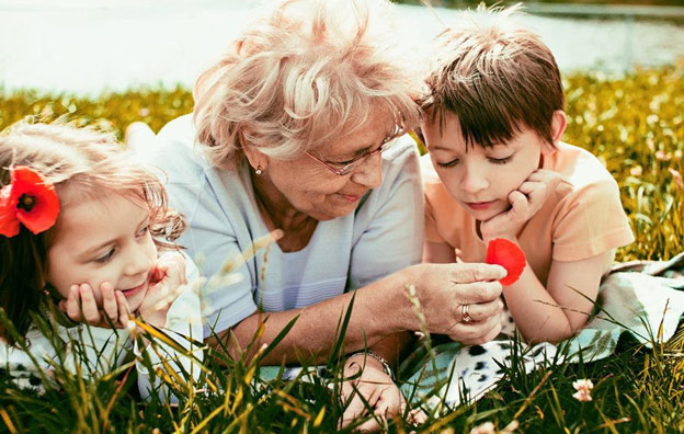 grandmother laying in the grass with her two grandchildren