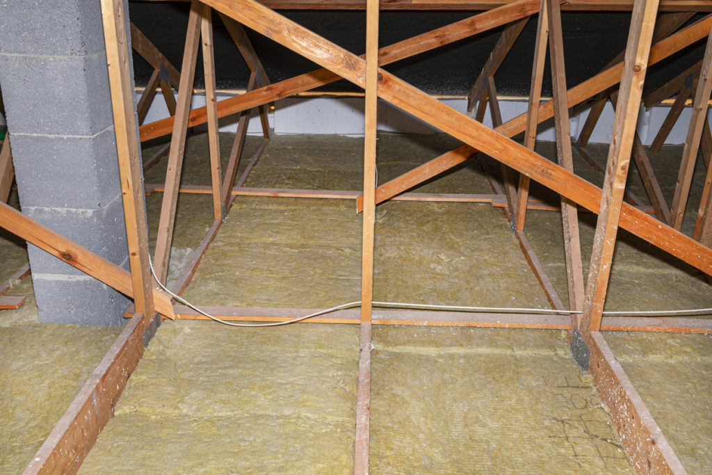 Ceiling and attic floor insulation made of rock wool between the trusses, visible system chimney.