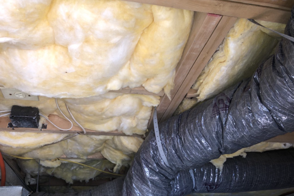 before picture of old insulation in floor joists