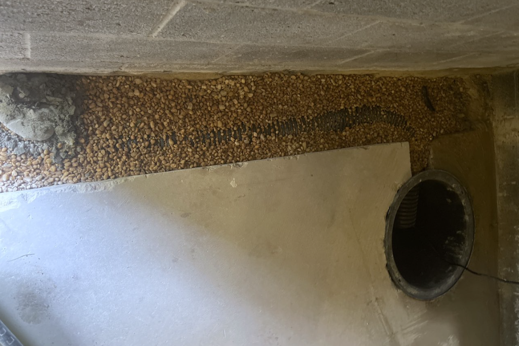 Interior French drain trench dug out and filled with gravel connected to sump pump basin